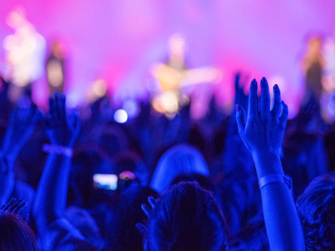 A crowd of people raising their hands at a church event.