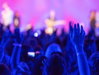 A crowd of people raising their hands at a church event.