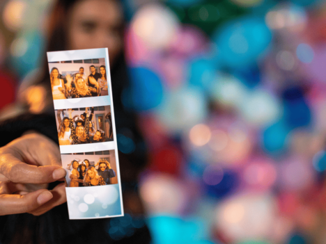 A woman holding up a photo with balloons in the background.